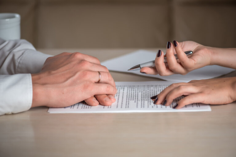 Hands of contractual parties, a woman and a man, signing a contract: business, premarital, loan, mortgage, credit, sales and purchase, investment agreement, divorce documents or other papers