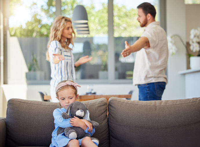 two parents yelling with child holding teddy bear on coach - child custody concept