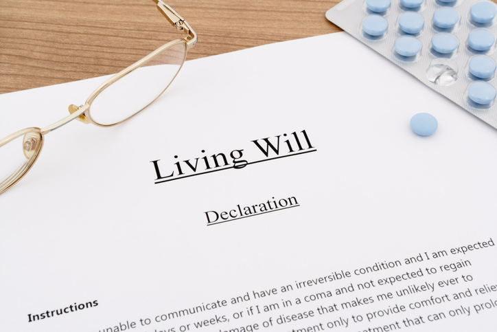 living will with pills and eyeglasses on wooden table