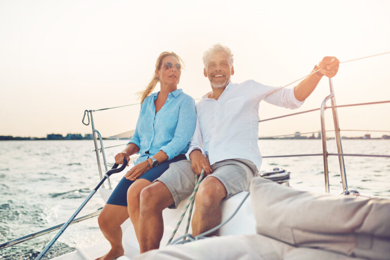 mature couple sitting on the deck of their boat while enjoying a day together sailing on a sunny afternoon