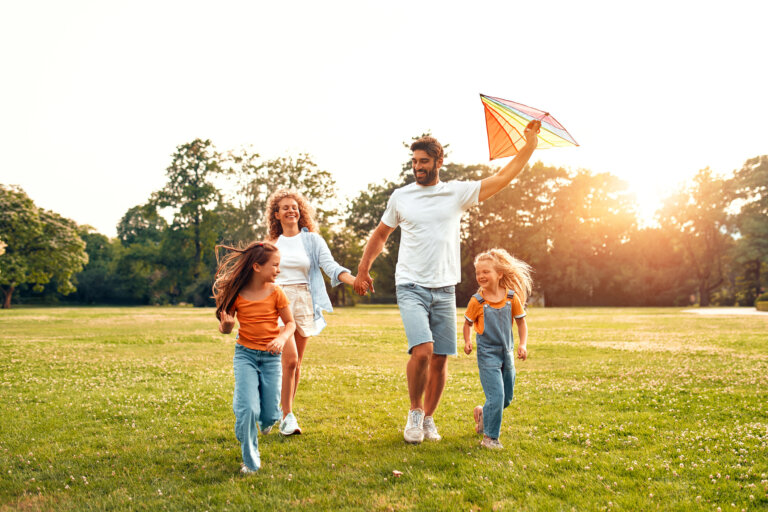“Family with two children running and flying a kite in a park at sunset.”