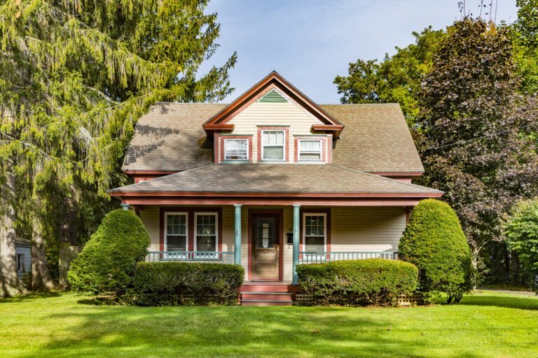 “Two-story house with front porch, dormer windows, and landscaped yard.”