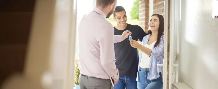 “Smiling couple accepts keys at their new home.”