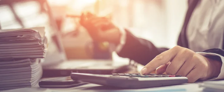 “Businessperson using calculator and reviewing financial documents.”