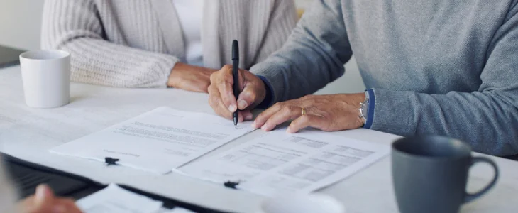 “Close-up of people signing estate or financial documents.”