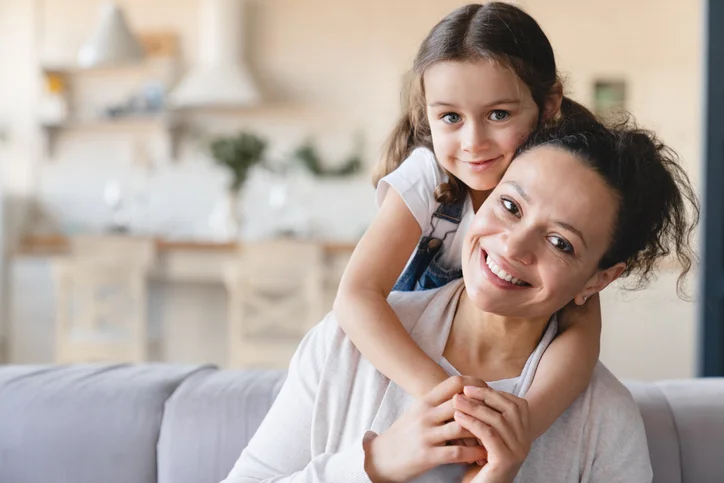 Happy caucasian mother and cute little daughter girl hugging embracing , spending time together looking at camera at home. Love and care, family moments, parenthood and motherhood concept