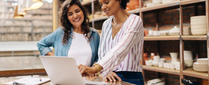 “Two women entrepreneurs working on a laptop in a shop.”