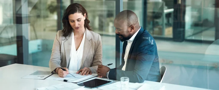caucasian woman and african american male at an office desk over looking a contract
