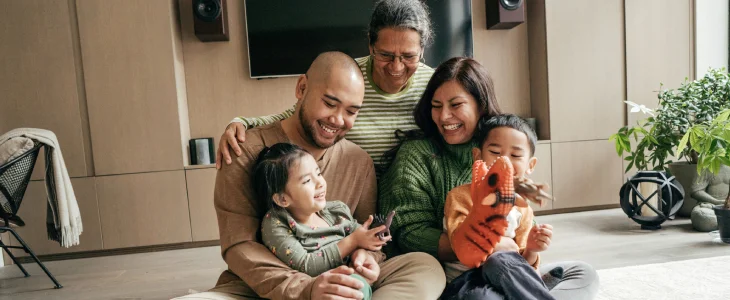 “Parents, children, and grandparent laughing and playing indoors.”