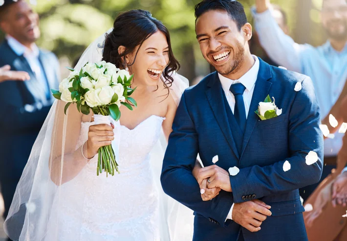 Newlyweds are greeted with festive confetti. Joyful bride and groom celebrating their wedding day with friends and family in the background