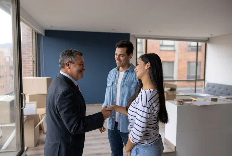 Real Estate Agent selling an apartment to a couple and closing the deal with a handshake - real estate concepts