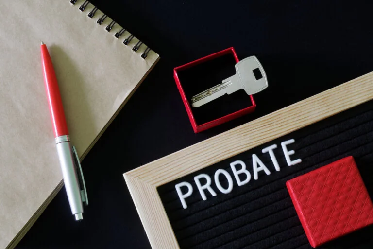 The inscription probate on a black board next to a notepad, pen and key in a red gift box. The concept of unexpected inheritance and memory of the testator. Close-up