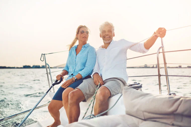 mature couple sitting on the deck of their boat while enjoying a day together sailing on a sunny afternoon