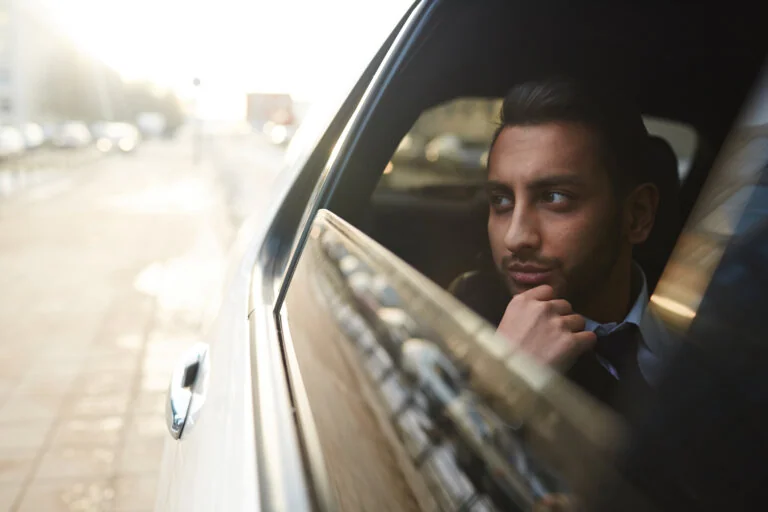 Man looking thoughtfully out of a car window.